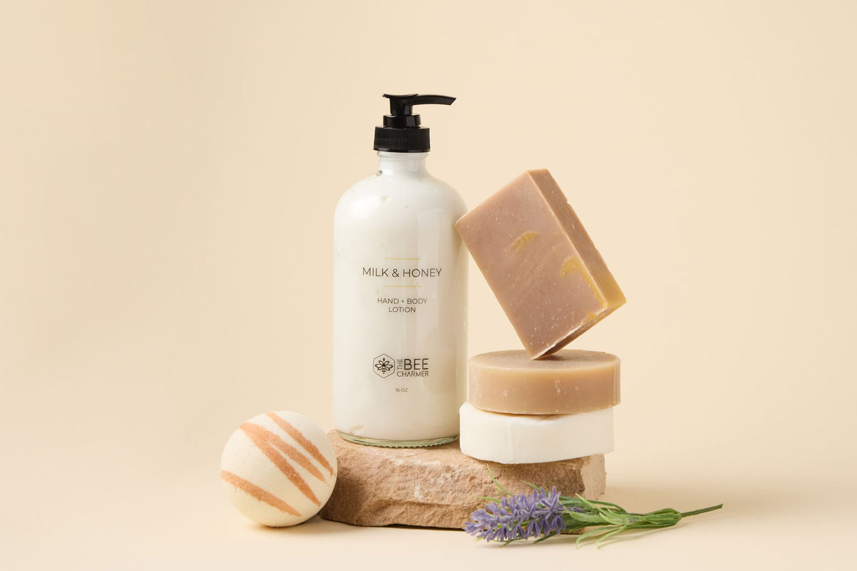 Milk & Honey Signature Set: hand & body lotion, bar soap and a bath bomb arranged on a stone slab with fresh lavender